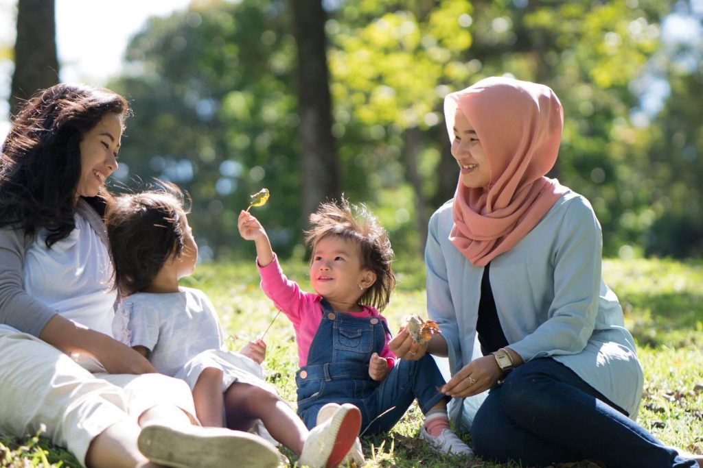 Family and two children laughing in the park.