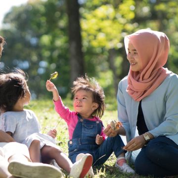 Family and two children laughing in the park.