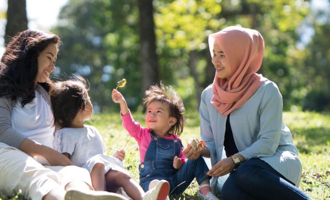 Family and two children laughing in the park.