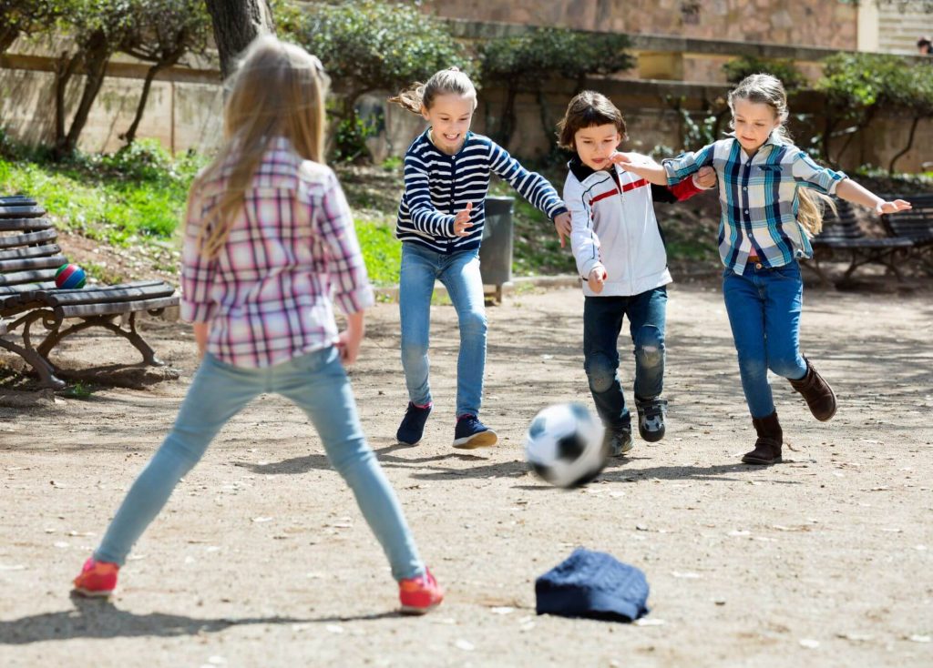 Kids playing soccer in a park.