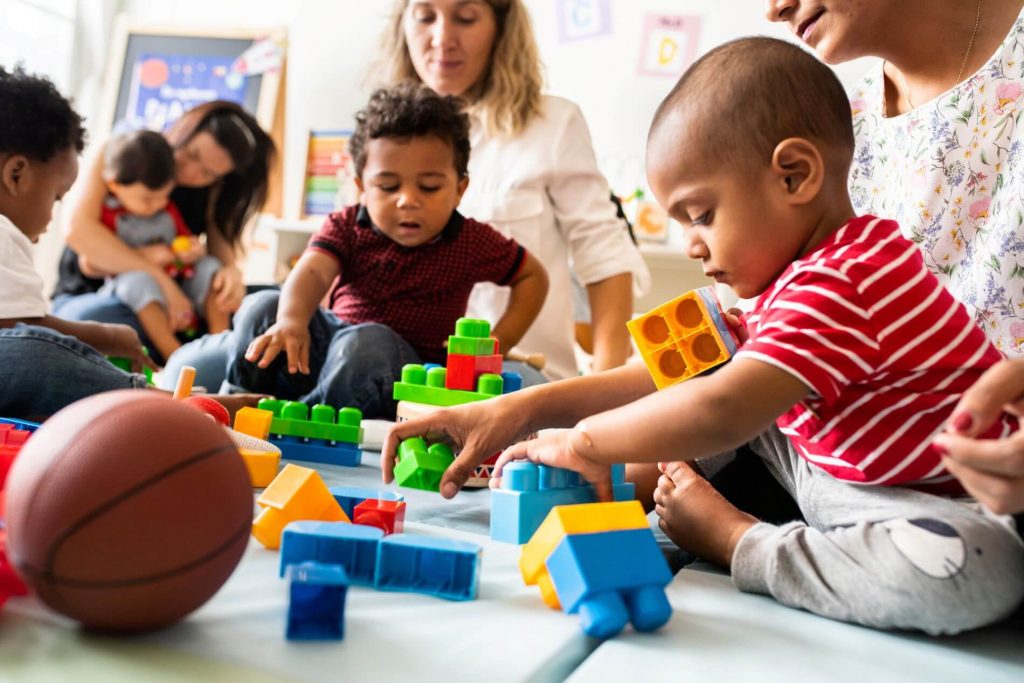 Children and parents playing with blocks and toys at school or daycare.