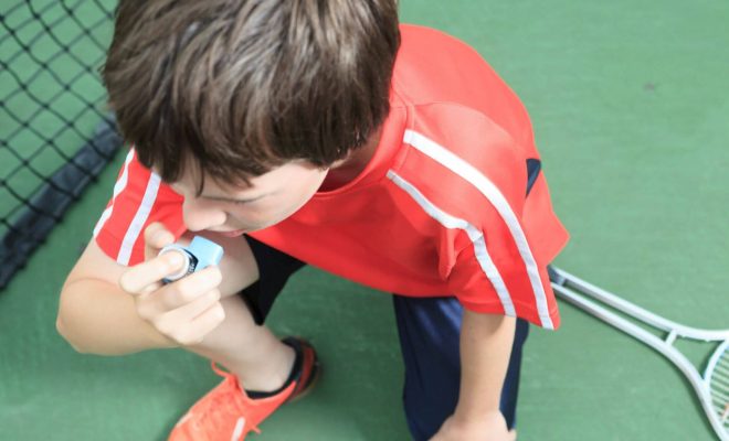 Child using inhaler after playing tennis.