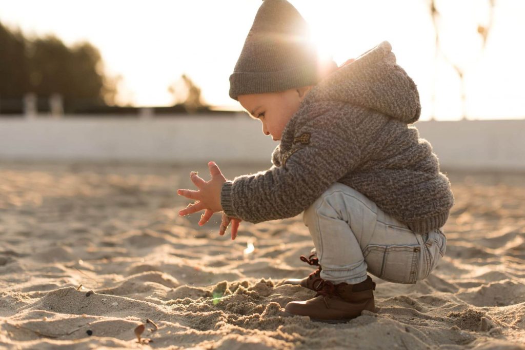 Toddler playing in a sandbox.