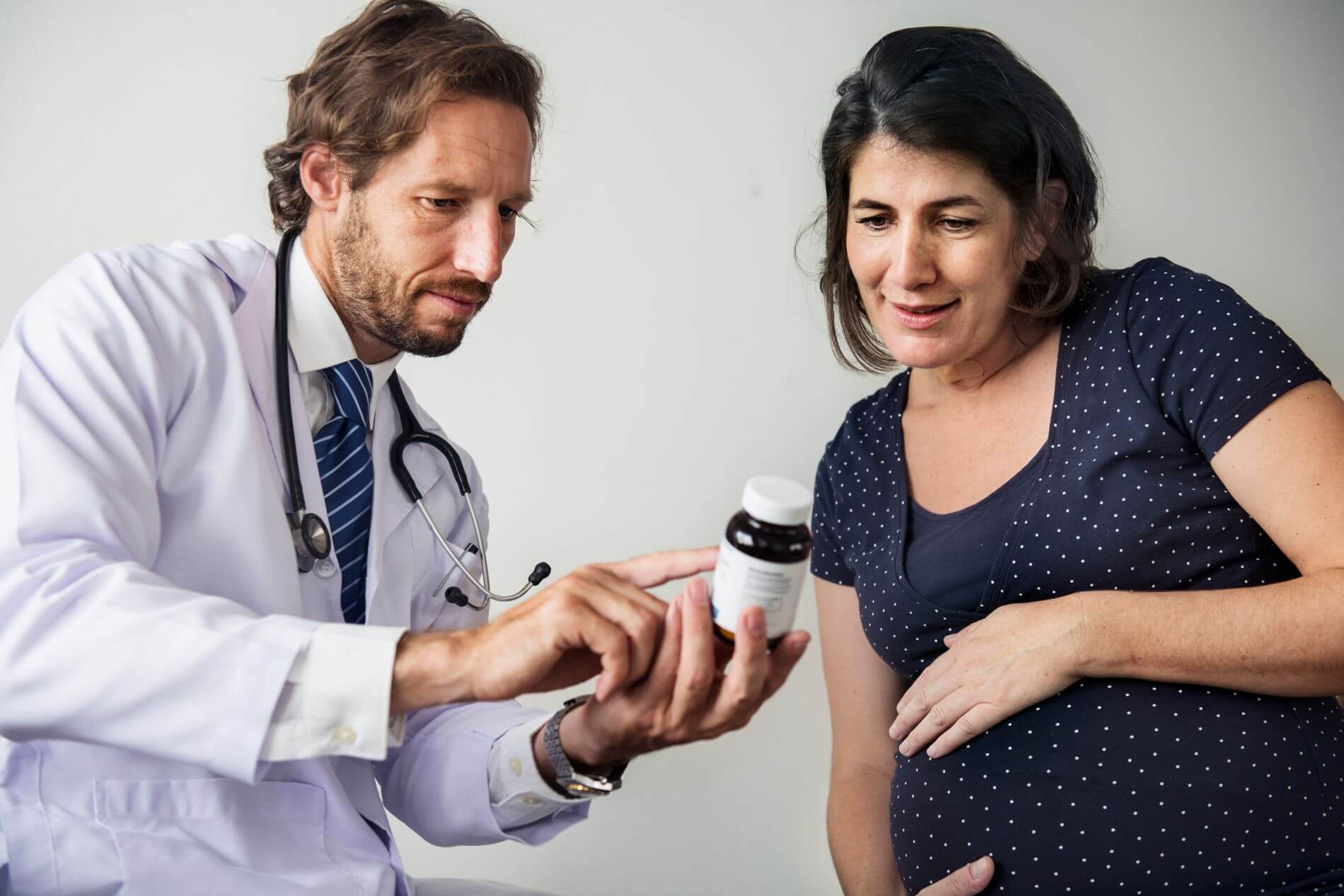 Pregnant woman talking with doctor while looking at medicine ingredients.