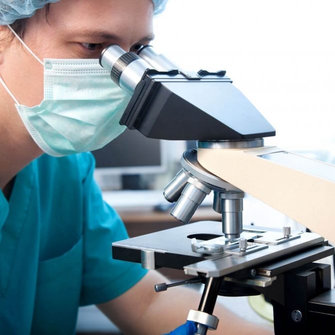 Researcher looking into a microscope in a lab.