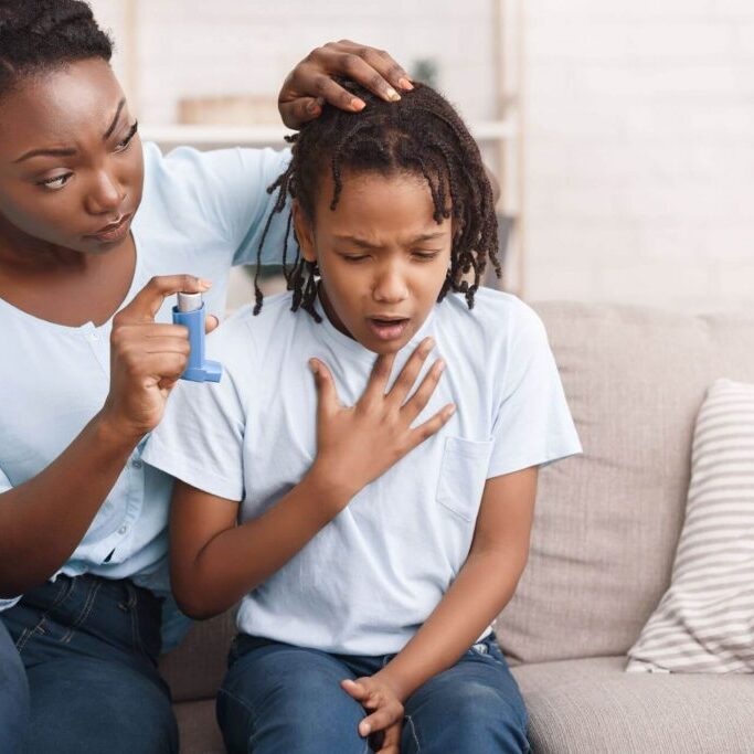 Mother giving child inhaler as he has an asthma attack.