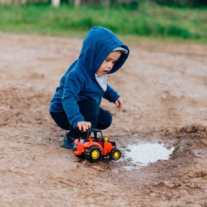 Baby playing with truck in the mud.